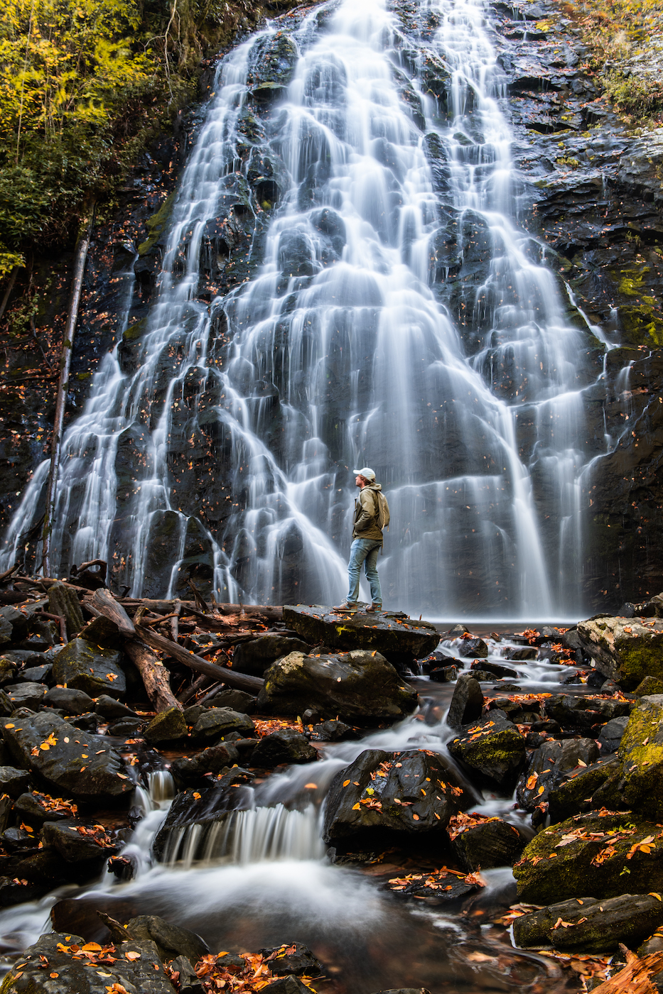 a person dedicated to conservancy stands in front of a waterfall