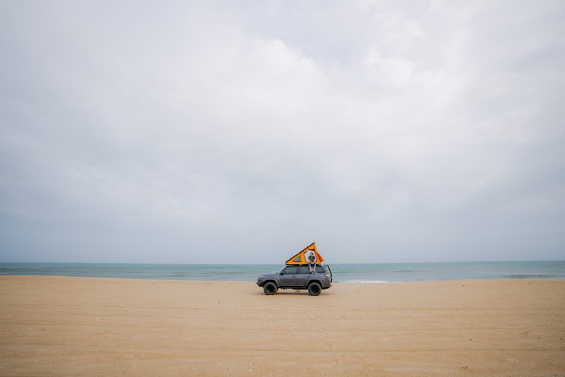 car on the sand with the ocean behind it