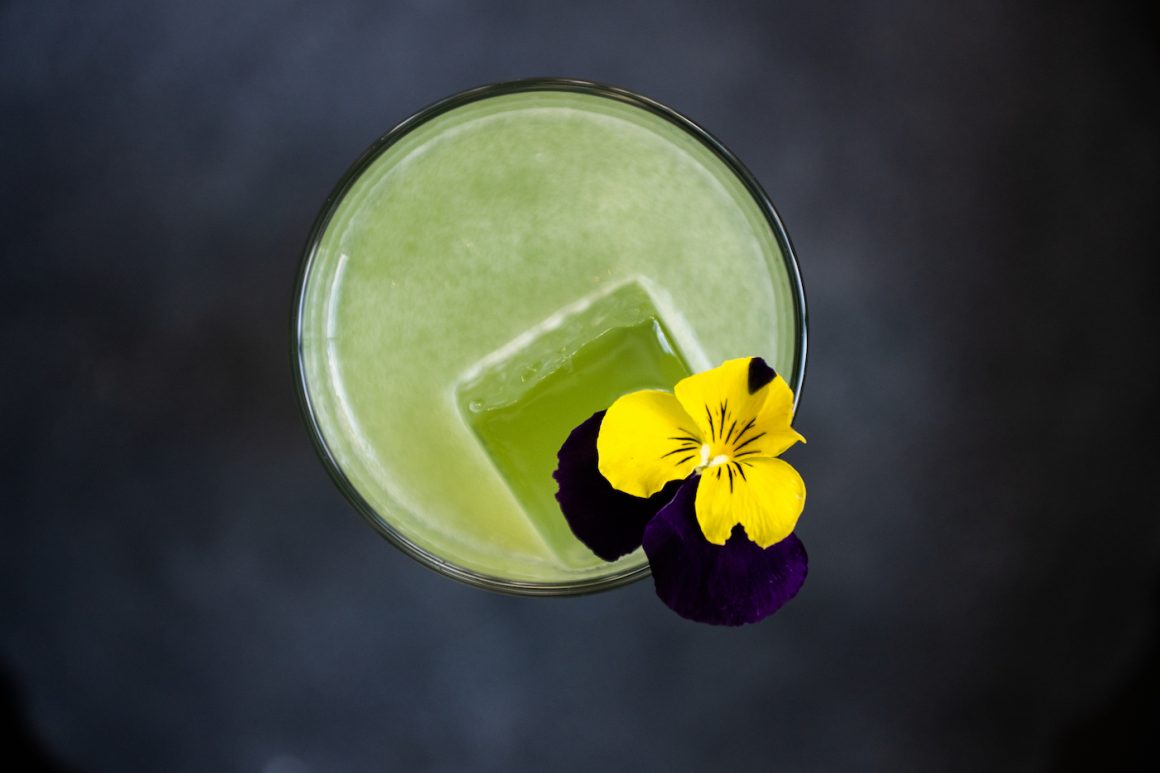 green cocktail with a yellow decorative flower shot from above