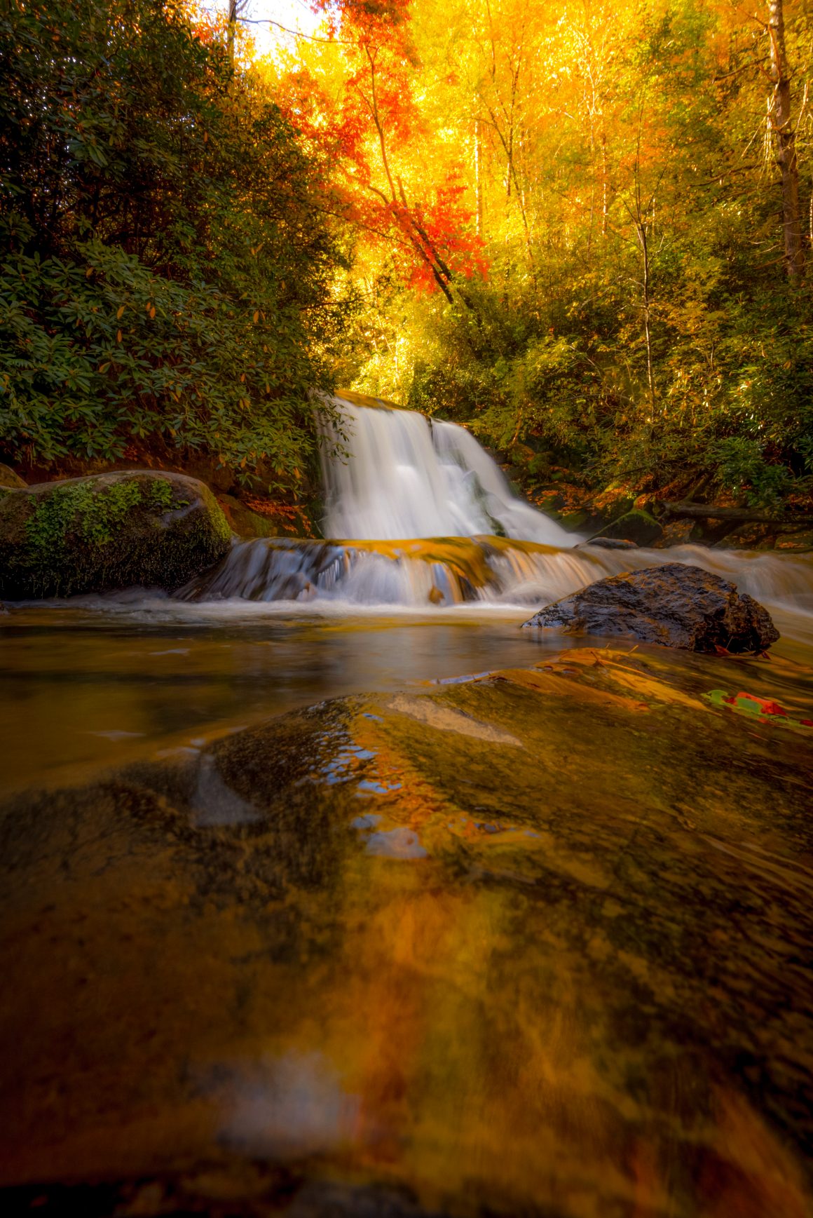 fall colors reflecting in a pool beneath a waterfall