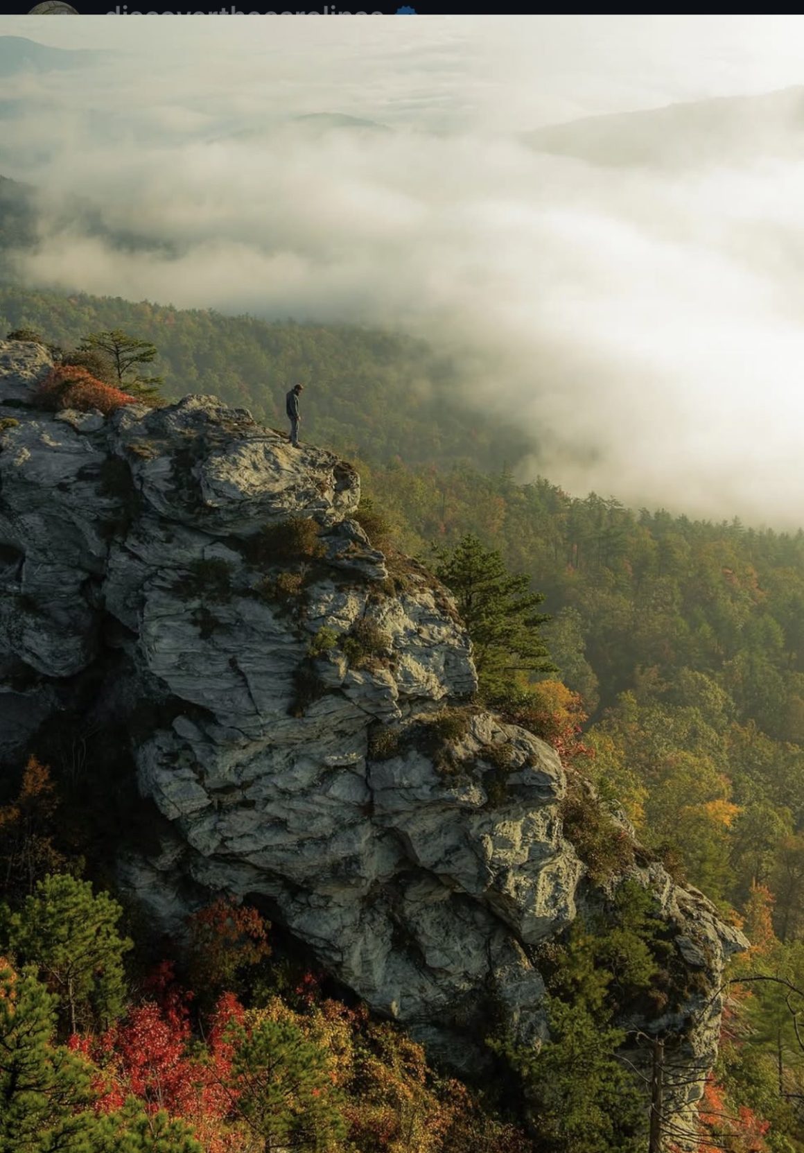 a hiker on a rocky cliff during fall